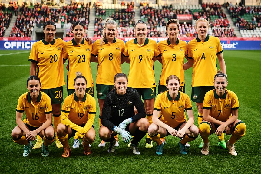 A team of soccer players wearing yellow and green line up for a photo before a game