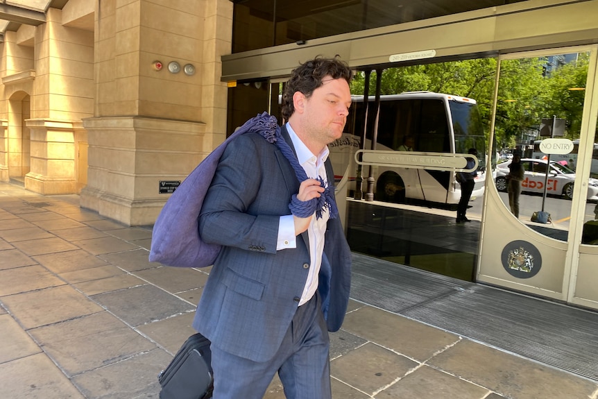 A man wearing a suit walking outside court. 