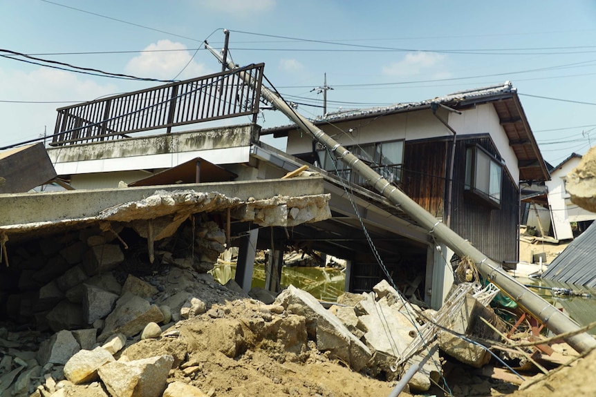 A power pole lies over the ruins of a house damaged in flooding.