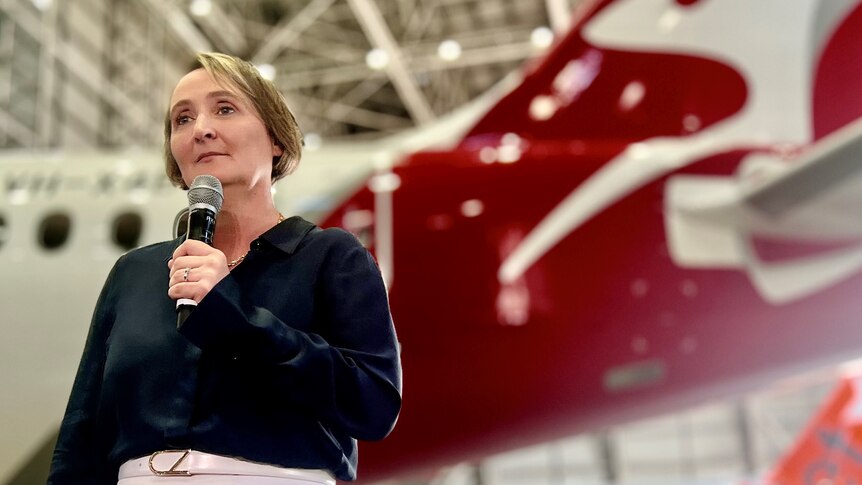 Midshot of Qantas CEO Vanessa Hudson standing in front of Qantas and Jetstar planes in a hanger.
