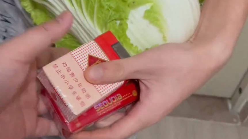 A still from a video showing a cabbage being exchanged for cigarettes.