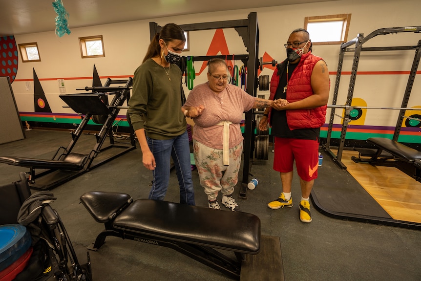 Woman being supported by two health professionals in a rehab clinic. 