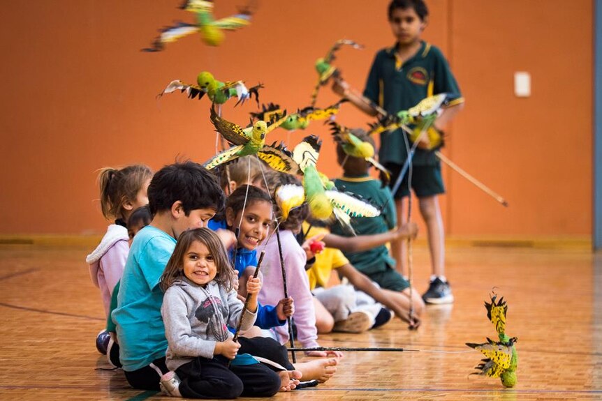 School kids from Western Australia city Kalgoorlie-Boulder performing with budgerigar puppets in an auditorium.