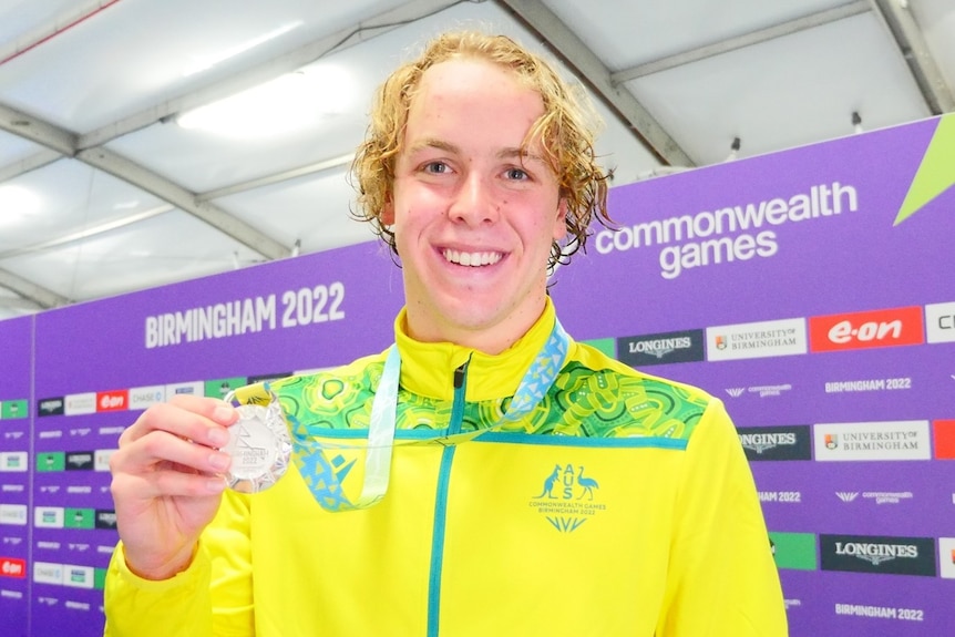 Sam Short smiles and holds up his silver medal.