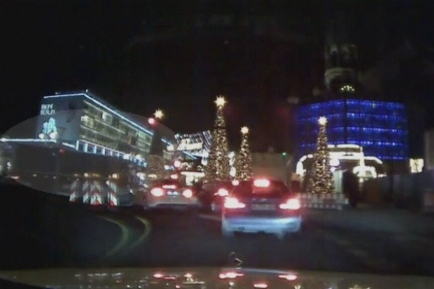 A video still showing a black truck driving through an intersection.