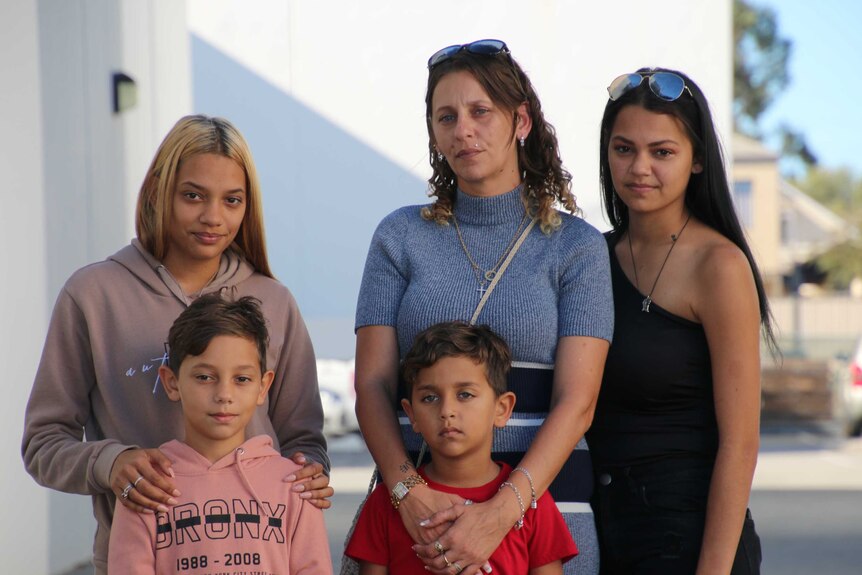 The family of Denishar Woods stand posing for a photo, with mother Lacey Harrison flanked by four children.