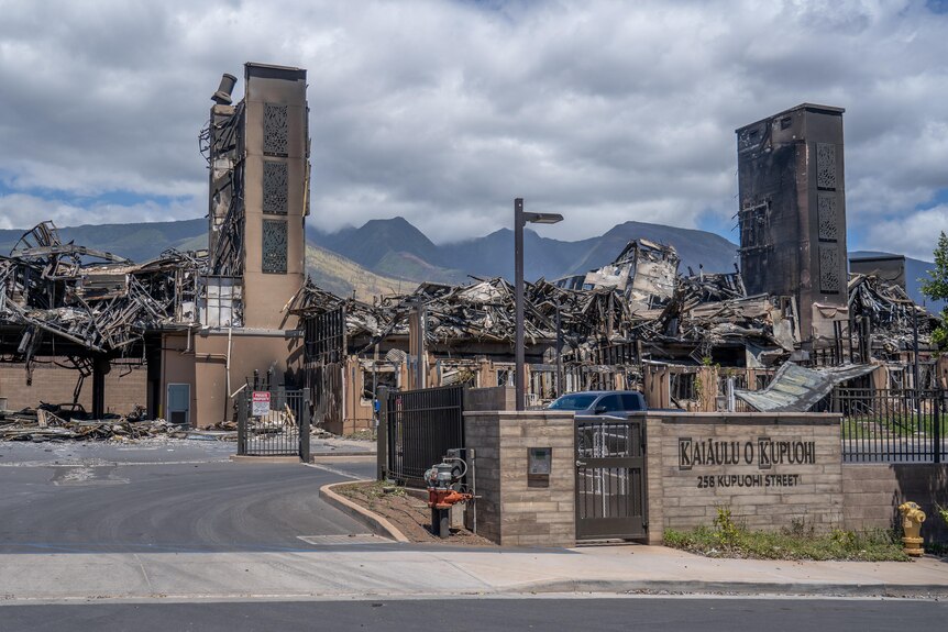 An apartment building is completely destroyed. The elevator shaft remains standing. Mountains are in the background.