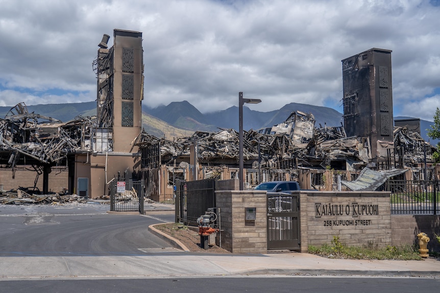 An apartment building is completely destroyed. The elevator shaft remains standing. Mountains are in the background.