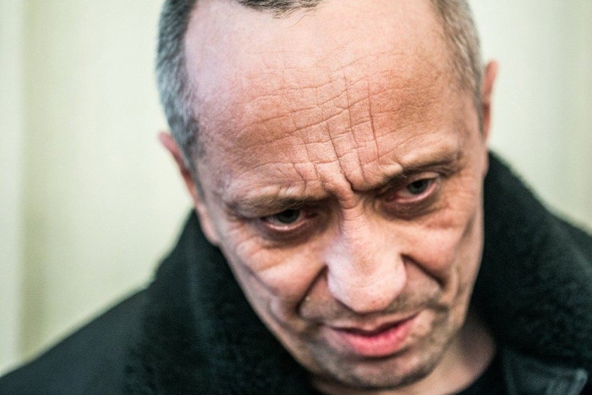 A close up of a man in aged in his late 50s, with a serious expression on his face.