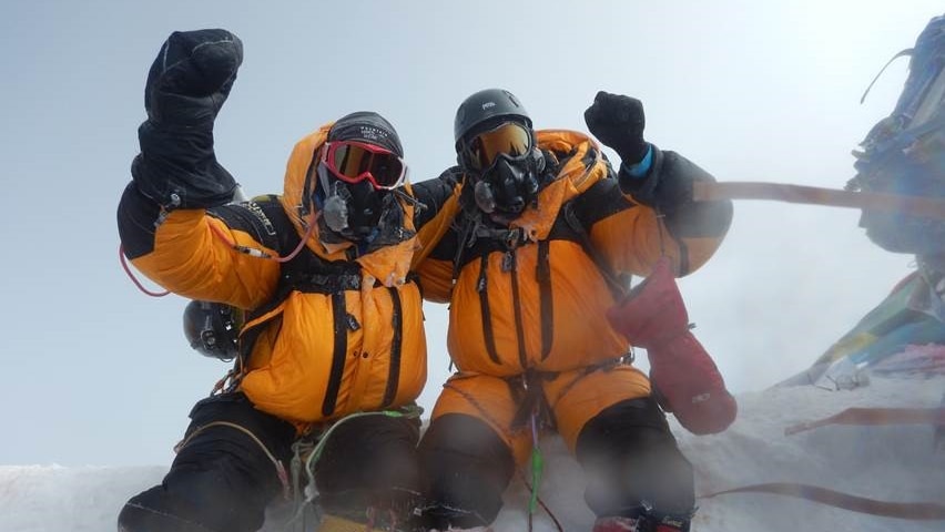 Two men in snow gear jubilant after climbing Mount Everest.