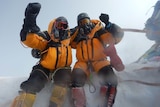 Two men in snow gear jubilant after climbing Mount Everest.