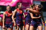 Players celebrate victory in an AFLW match