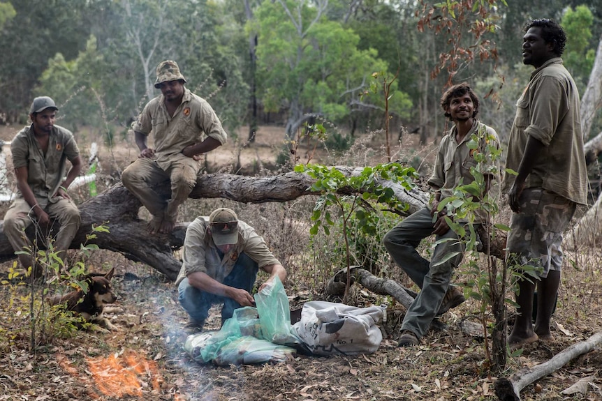 Warddeken rangers sit around a fire and cook up a meal in Arnhem Land.