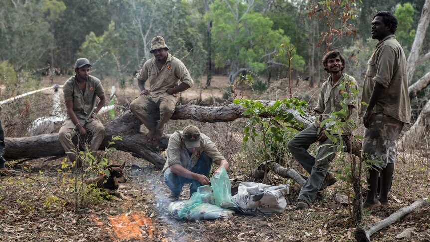 Warddeken rangers sit around a fire and cook up a meal in Arnhem Land.