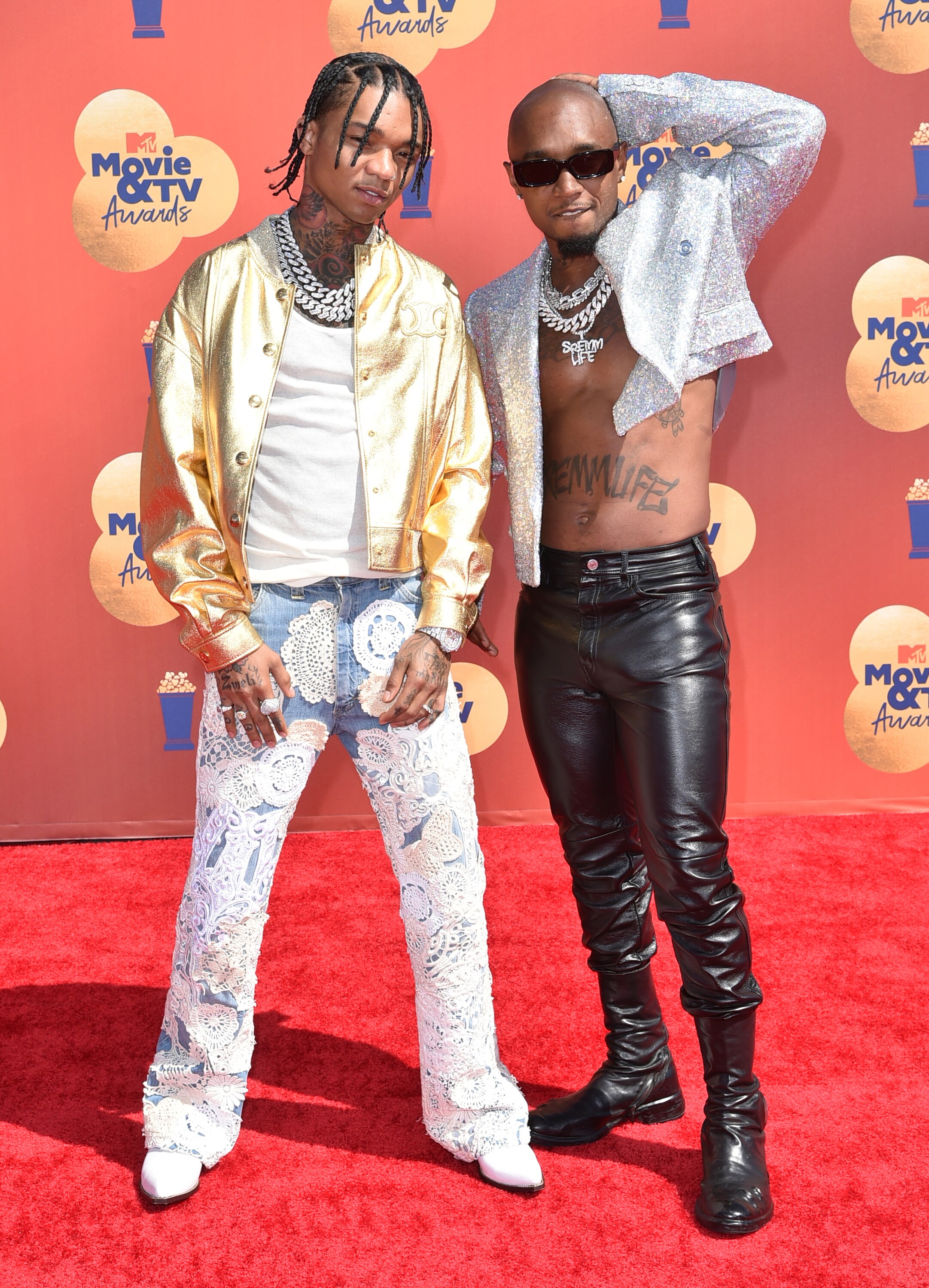 Swae and Slim pose on the red carpet. Saw is in jeans a gold jacket while Slim wears black leather pants and a silver top.