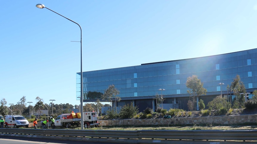Workers dismantle the barbed-wire fence that surrounds the ASIO building on Parkes Way.