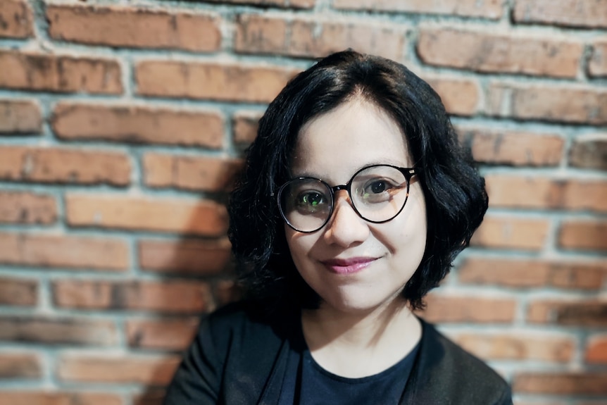 A woman wearing glasses smiling to camera