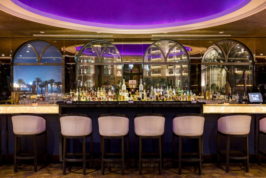 A hotel bar with chairs, alcohol, and lights