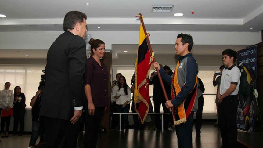 Klaus Jungbluth stands with the flag of Ecuador at a presentation ceremony.