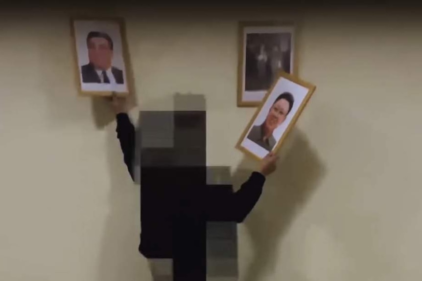 A screenshot from the Cheollima video purportedly showing a pixelated figure removing portraits of North Korean leaders.
