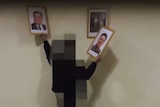 A screenshot from the Cheollima video purportedly showing a pixelated figure removing portraits of North Korean leaders.