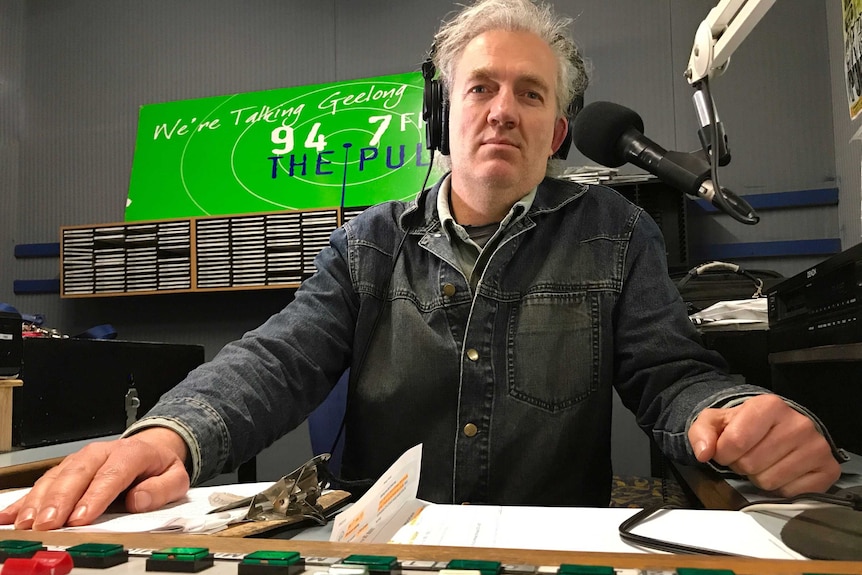 Leo Renkin sits in a radio studio with headphones on his head.