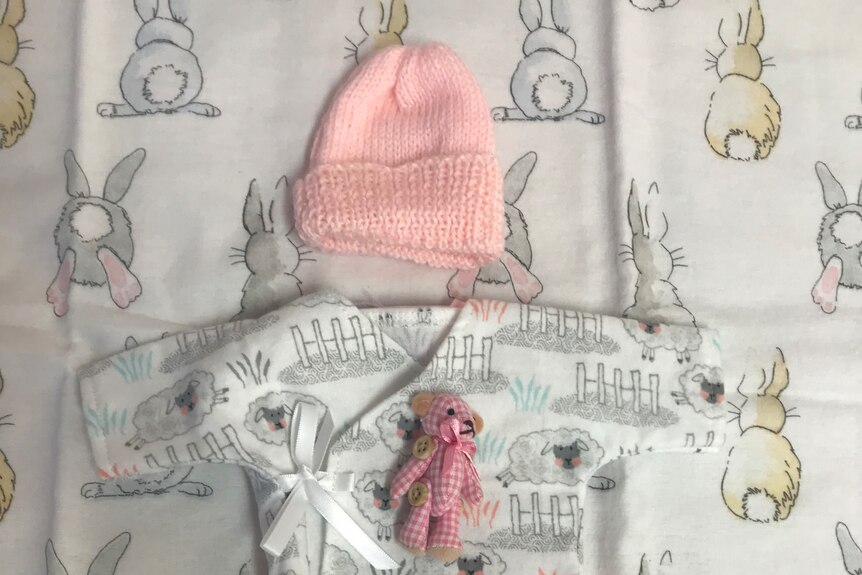 An arrangement of small white and pink baby clothes 