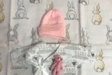 An arrangement of small white and pink baby clothes 