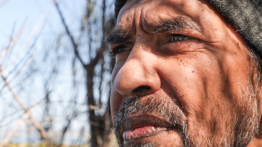 Close up of Warren Foster with the dappled shadow of a Melaleuca tree on his face