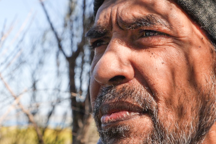 Close up of Warren Foster with the dappled shadow of a Melaleuca tree on his face