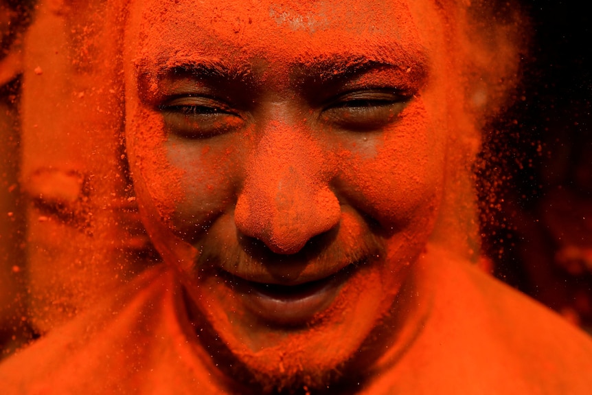 A devotee smiles while being smeared with vermilion powder
