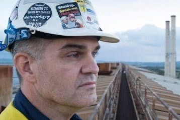 Man wearing hard hat standing on roof of coal-fired power station