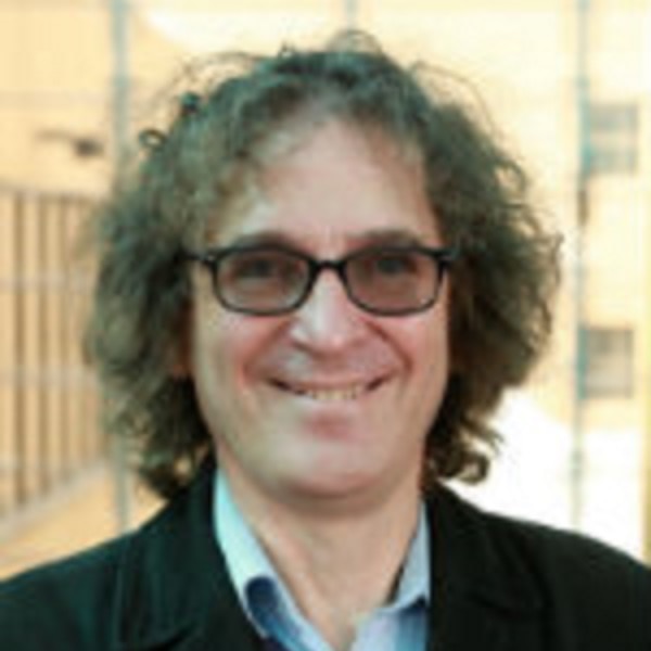 A man with long curly hair wearing glasses
