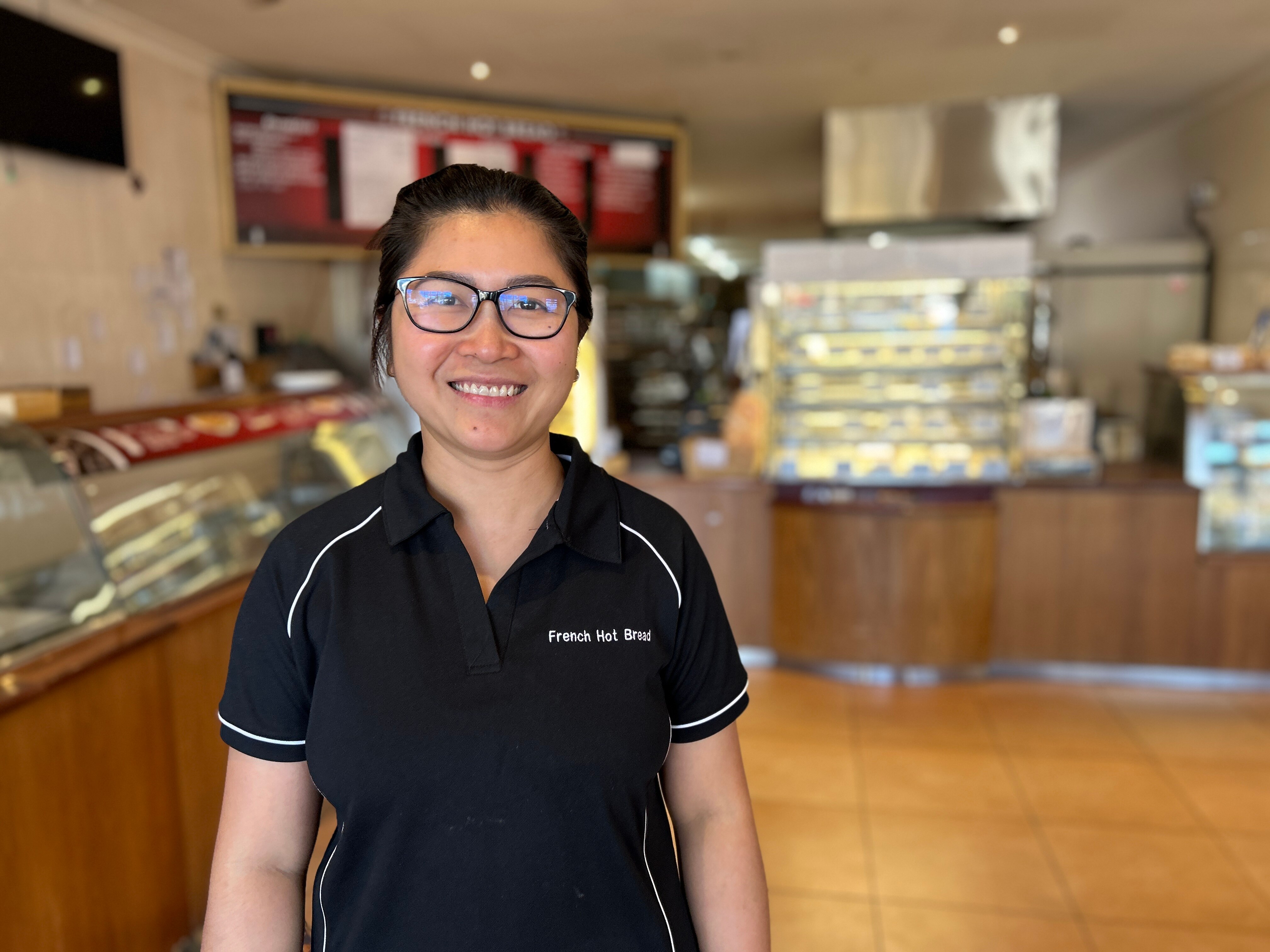 A woman stands in a bakery.