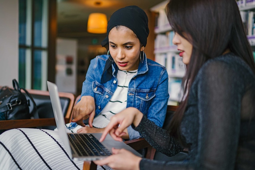 Two women look at a laptop together