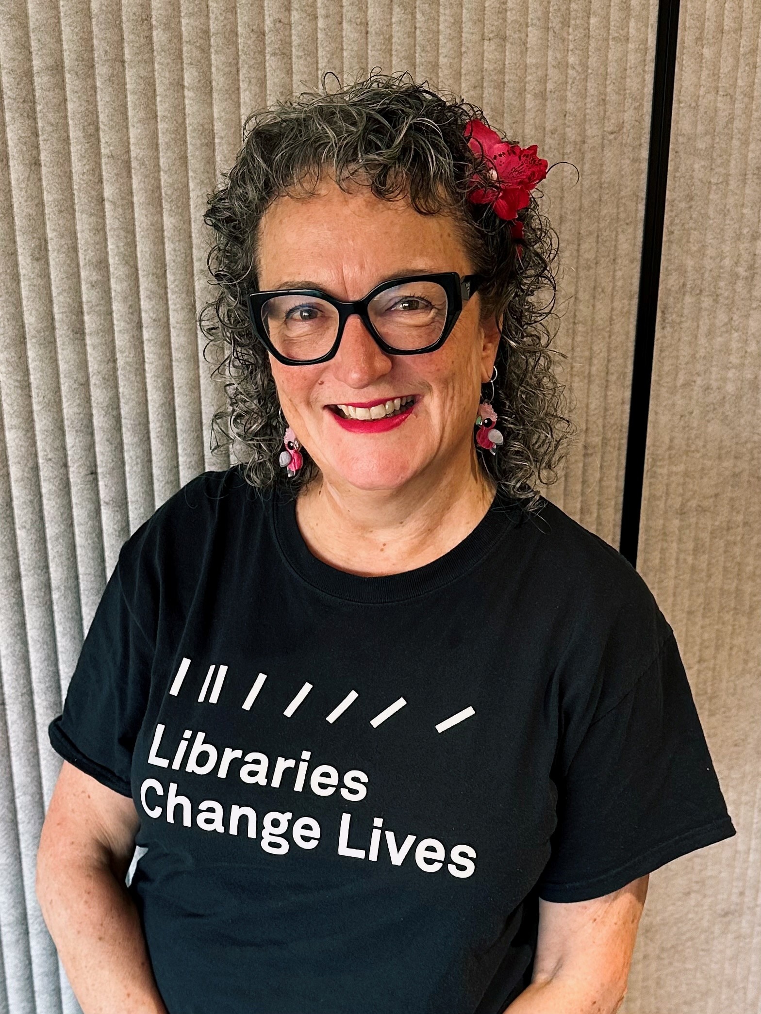 A woman with curly hair wears a black tshirt that says Libraries Change Lives.