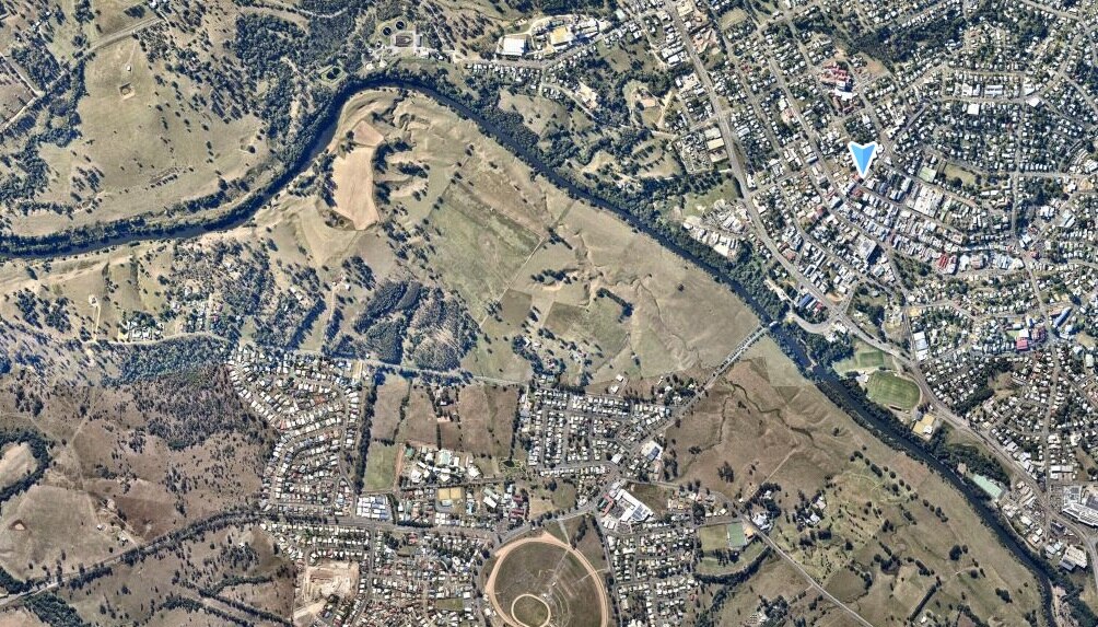 An aerial shot of the gympie region, green farming land mixed with the riverside rooftops of the town. 