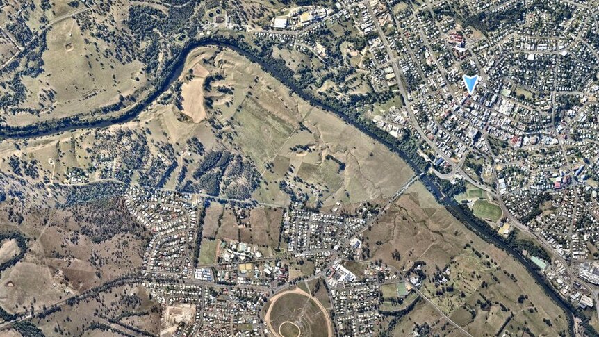An aerial shot of the gympie region, green farming land mixed with the riverside rooftops of the town. 