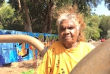 Aboriginal woman Helen Fejo-Frith stands next to a water pipeline fixture.