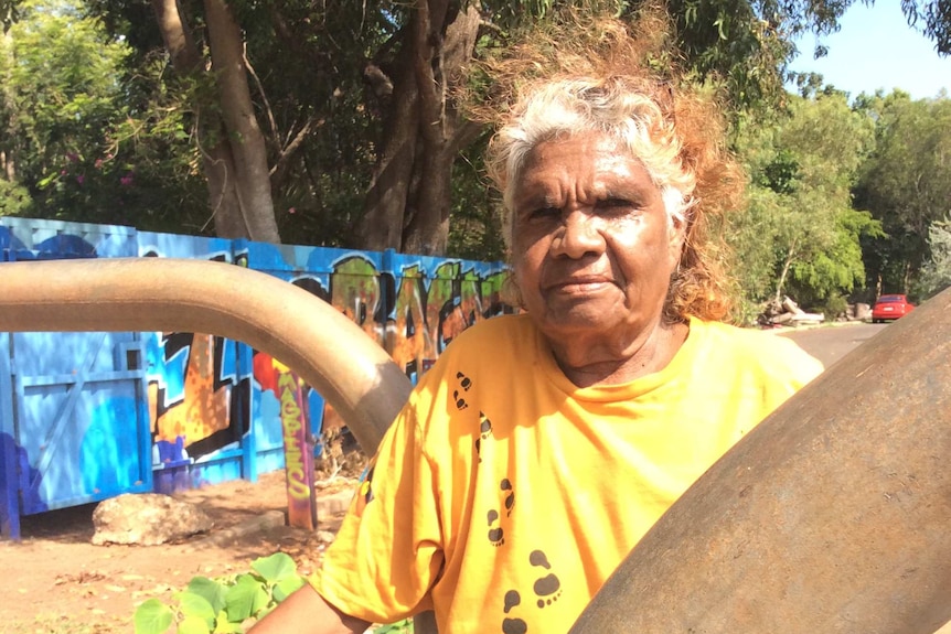 Aboriginal woman Helen Fejo-Frith stands next to a water pipeline fixture.