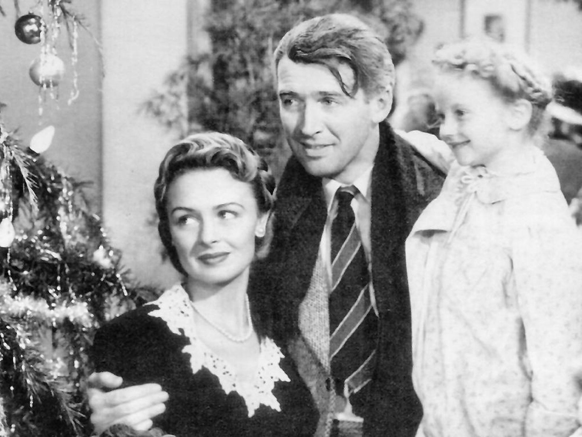 A still from It's a Wonderful Life, showing Donna Reed, James Steward and child actor Karolyn Grimes