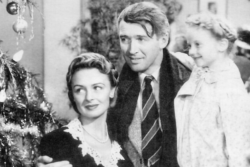 A still from It's a Wonderful Life, showing Donna Reed, James Steward and child actor Karolyn Grimes