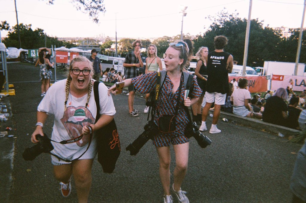 A film photo of two women are carrying multiple professional cameras at Laneway Festival