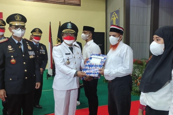 A number of people in formal attire and wearing masks during a certificate handover ceremony.
