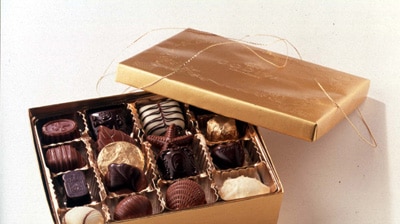 A generic chocolate box sits open, displaying gourmet chocolates inside.