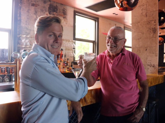 Connections owner Tim Brown (blue shirt) clinks glasses with long-time patron Neil van Zee.