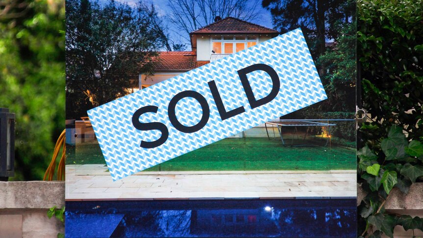 A sold sticker sits over a real estate for sale sign