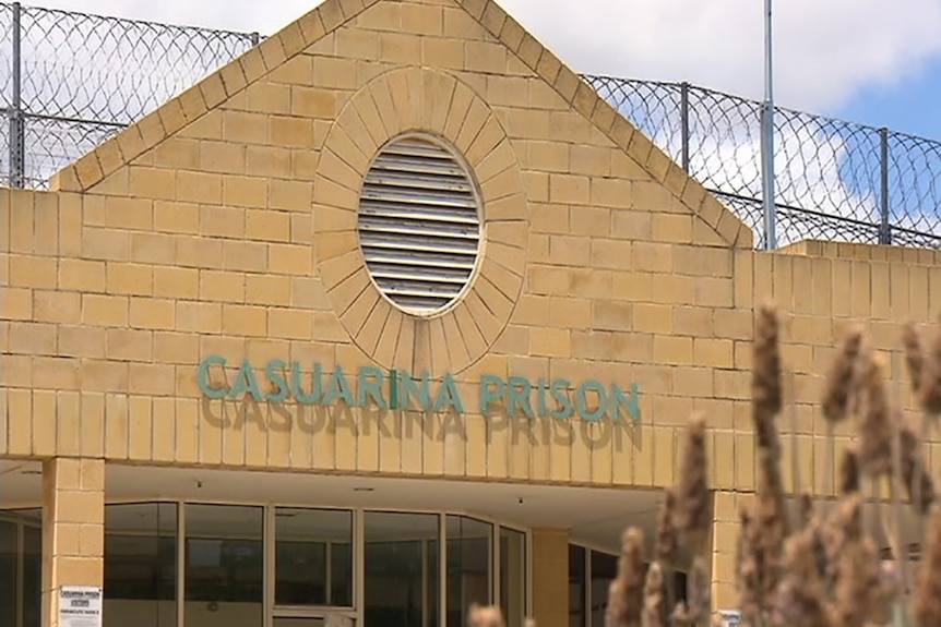 A close-up shot of the top of the front building at Casuarina Prison with barbed wire running along the top of it.