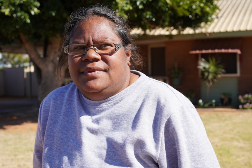 A head and shoulders shot of an Indigenous woman wearing spectacles outdoors.