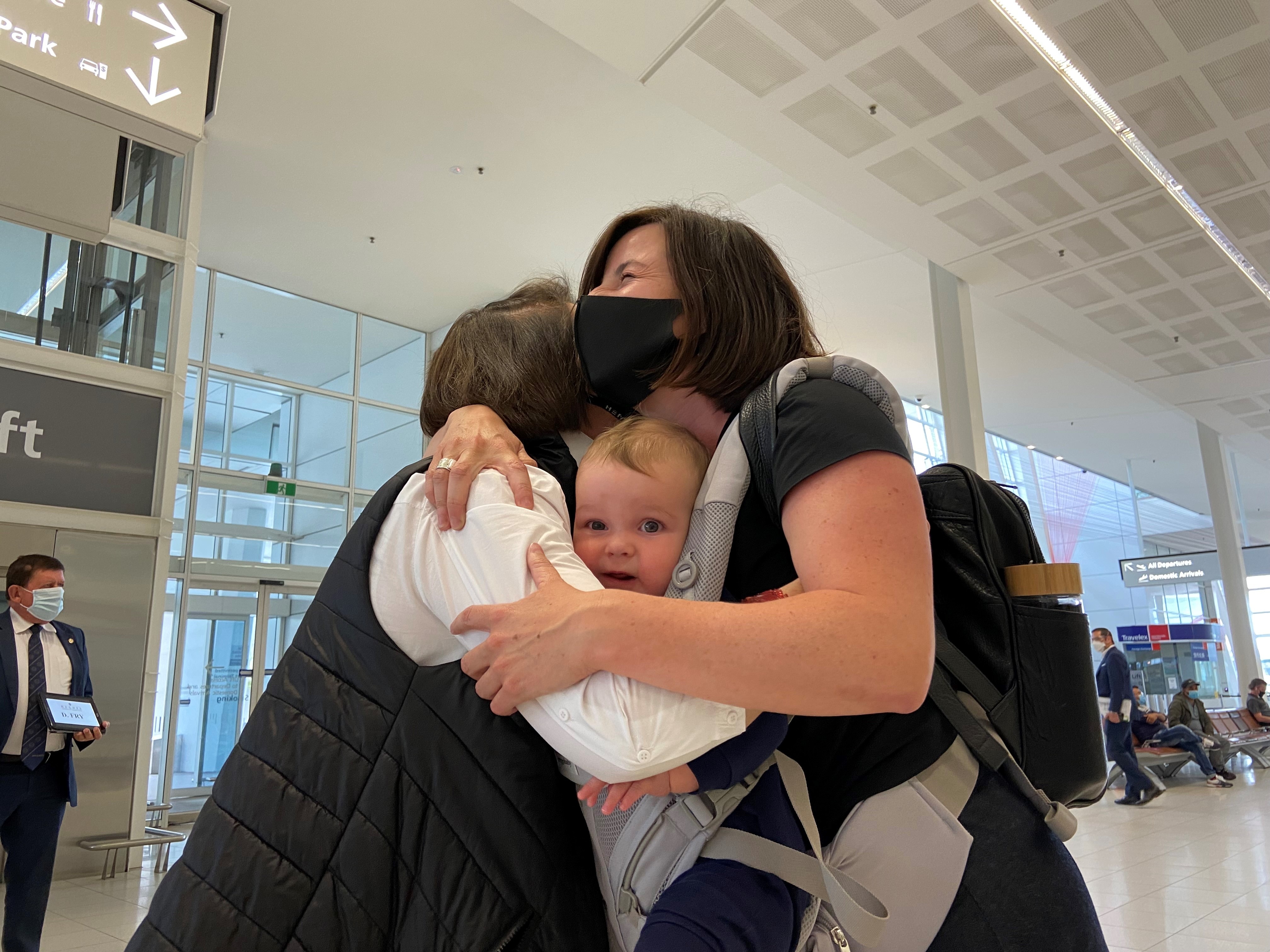 A group of people hug with a baby looking at the camera